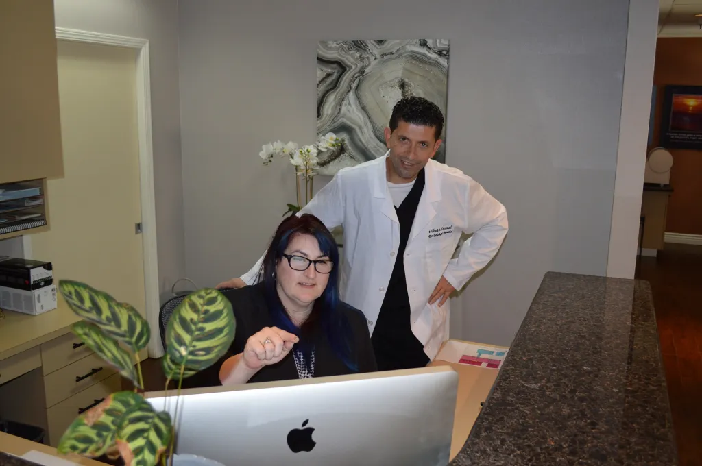 Doctor Bouzid and office manager looking at the computer at front desk